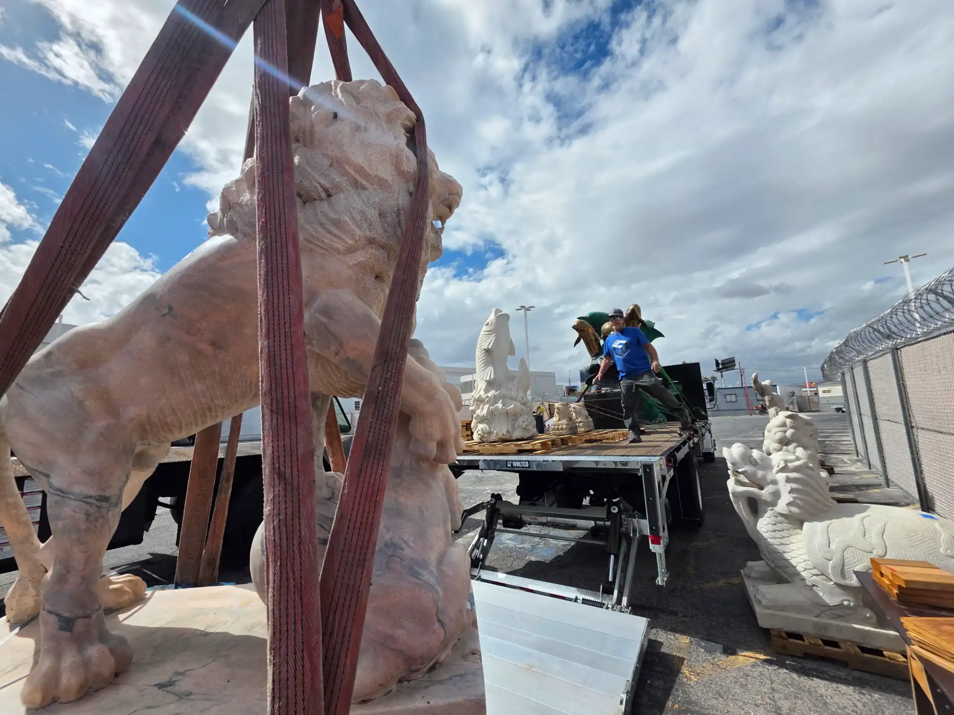 Marble lion and dragon statues staged for transport on a flatbed